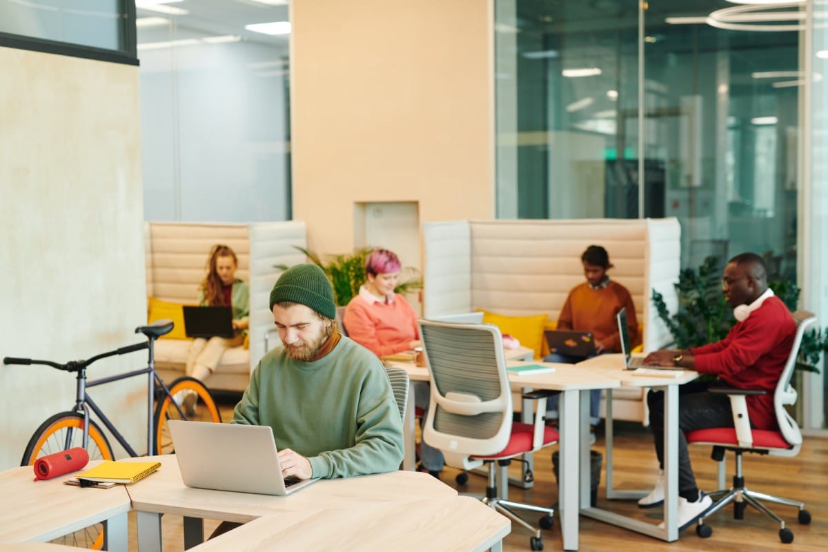 Espace de travail collaboratif moderne avec professionnels utilisant des outils IA sur ordinateurs portables pour optimiser leurs processus internes d'entreprise